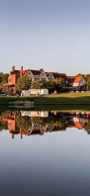 a golf course with a house reflected in the water