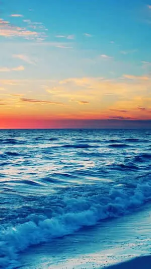 a beach with waves at sunset